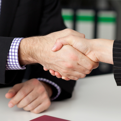 Businessman and businesswoman shaking hands at office desk_crop