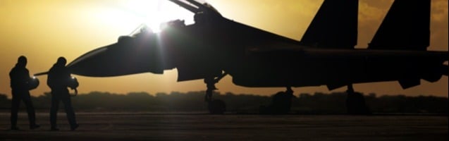 Two pilots approaching fighter jet with cockpit open.